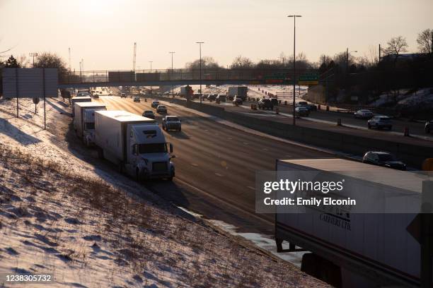 Trucks sit idle on Interstate 75 as cars drive by on February 8, 2022 in Detroit, Michigan. Due to Canadians protesting vaccine mandates, hundreds of...