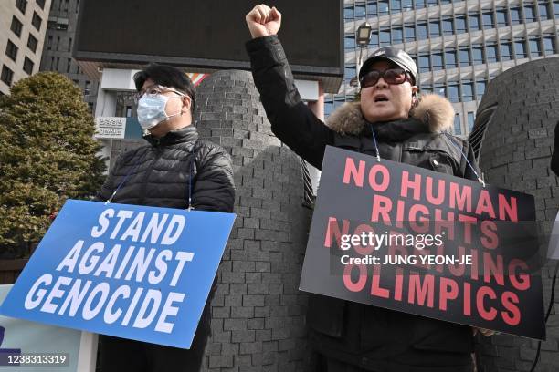 Protesters hold placards linking China's human rights record and the ongoing Beijing Winter Olympic Games, during a rally in front of the Chinese...