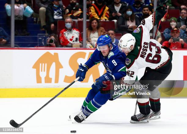 Miller of the Vancouver Canucks skates past Janis Moser of the Arizona Coyotes before scoring during their NHL game at Rogers Arena February 8, 2022...