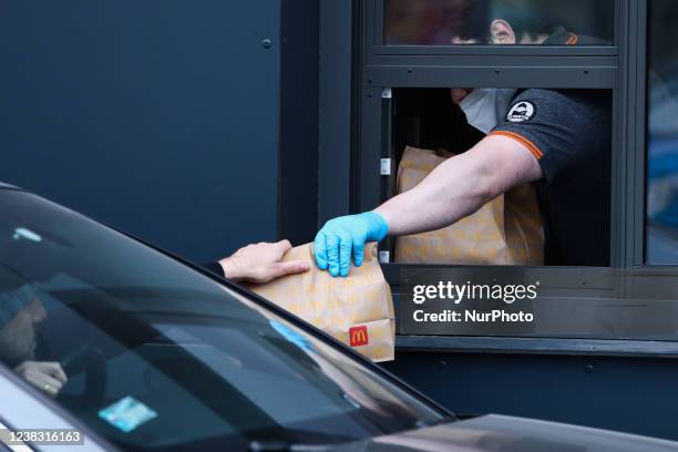 McDonald's worker wearing a protective gloves serves a meal to the client in a car in McDrive in Krakow Poland on February 7, 2022.