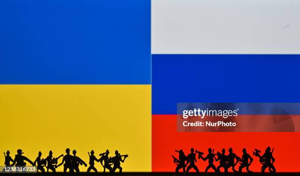 Illustrative photo of small figures of soldiers representing two armies in front of the flags of Ukraine and Russia displayed on a computer screen....