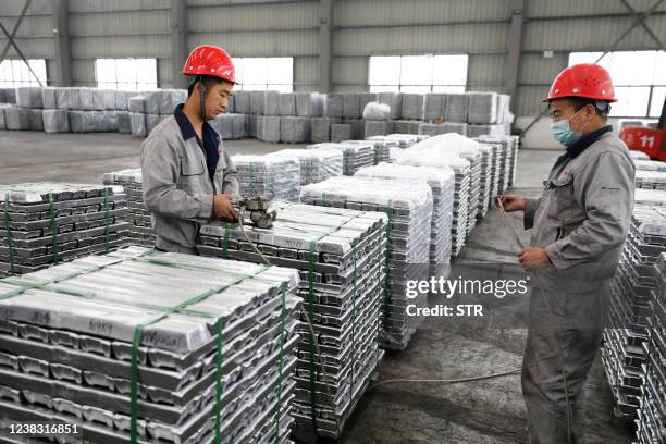 Employees work with aluminium ingots at a factory in Huaibei in China's eastern Anhui province on February 9, 2022. / China OUT