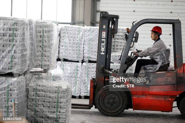 An employee transfers aluminium ingots at a factory in Huaibei in China's eastern Anhui province on February 9, 2022. / China OUT