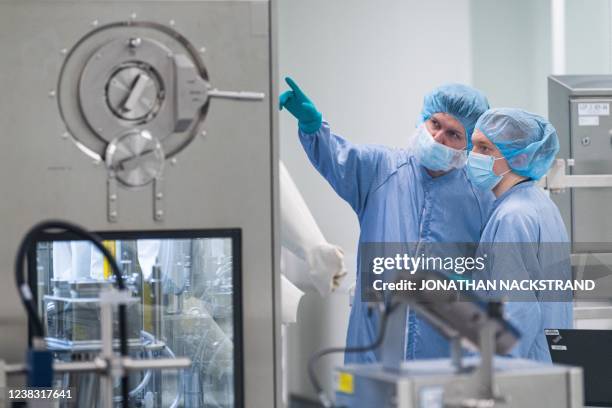 Employees in protective gear work at the aseptic filling section at the facility of pharmaceutical company AstraZeneca for biological medicines in...