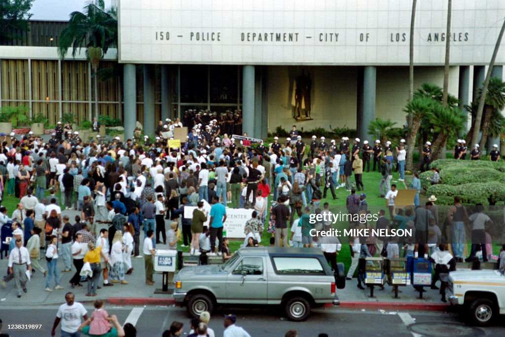 4521 Police Riot Police officers in riot gear stand by as angry demonstrators gather ...