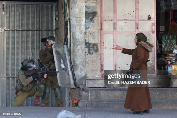 Woman gestures at Israeli security forces firing rubber-bullets to disperse Palestinian stone-throwers amid clashes in the West Bank town of Hebron,...