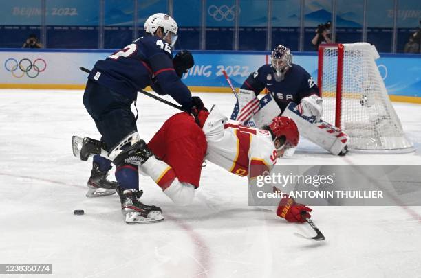 S Aaron Ness and China's Tyler Wong vie for the puck during their men's preliminary round group A match of the Beijing 2022 Winter Olympic Games ice...