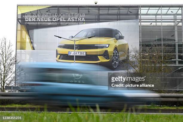 February 2022, Hessen, Rüsselsheim: A large poster showing a new Opel Astra is displayed at a parking garage near the Opel plant site. Series...