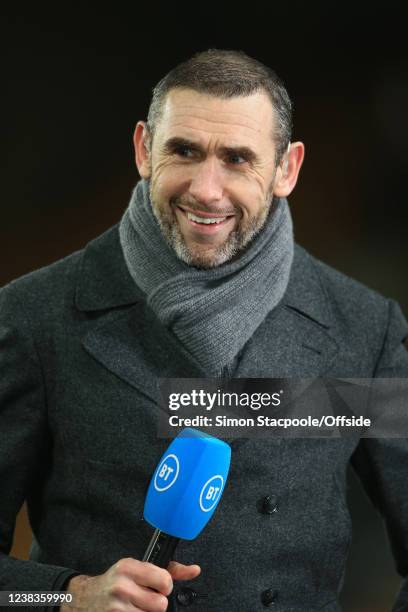 Martin Keown smiles as he holds the microphone whilst working for BT Sport during the Premier League match between Wolverhampton Wanderers and...