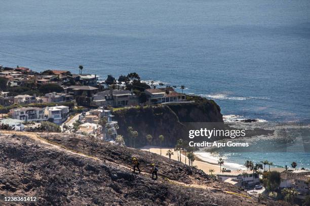 Firefighters monitors the situation on a smoldering hillside in Laguna Beach, California on February 10, 2022. A wind-driven brush fire that broke...