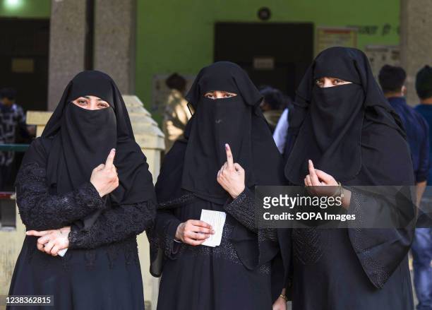 Indian Muslim women show their inked index finger after casting their ballots, during the first phase of Uttar Pradesh state assembly elections.