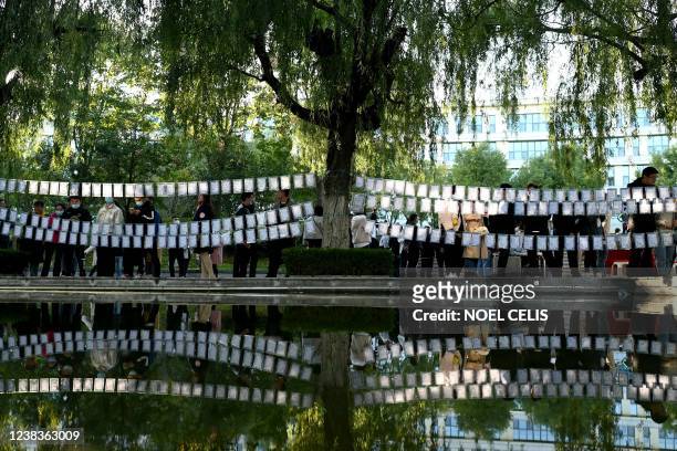 This photo taken on October 17, 2021 shows single people inspecting rows of profiles strung up between trees during a matchmaking event in Jinan in...