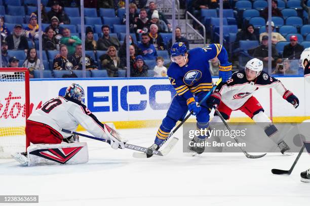 Elvis Merzlikins and Zach Werenski of the Columbus Blue Jackets defend against Tage Thompson of the Buffalo Sabres during an NHL game on February 10,...
