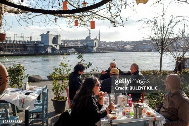 People drink raki, Turkish traditional alcohol, at Karakoy port, on February 10, 2022. - In this once buzzing Istanbul neighbourhood with popular...
