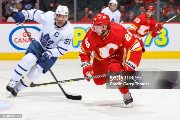 Elias Lindholm of the Calgary Flames skates up ice against John Tavares of the Toronto Maple Leafs at Scotiabank Saddledome on February 10, 2022 in...