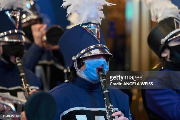 Musician with a hole cut into a face mask performs along with a marching band during the opening night of Broadway musical "The Music Man" at Winter...