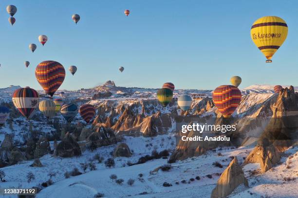 Hot-air balloons glide over snow covered fairy chimneys in the Cappadocia in Goreme district of Nevsehir, Turkiye on February 11, 2022. Cappadocia is...