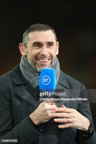Martin Keown smiles as he holds the microphone whilst working for BT Sport during the Premier League match between Wolverhampton Wanderers and...