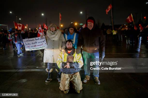 Protestors stand in front of a police cruiser as a 7pm injunction deadline comes into affect at a blockade at the foot of the Ambassador Bridge,...