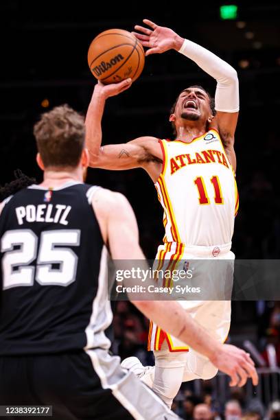 Trae Young of the Atlanta Hawks winces as he goes up for a shot against Josh Primo of the San Antonio Spurs during the second half of a game at State...
