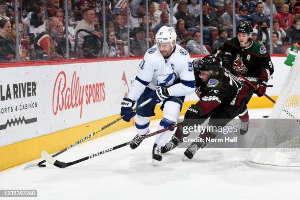 Steven Stamkos of the Tampa Bay Lightning skates with the puck while being defended by Travis Boyd of the Arizona Coyotes during the second period at...