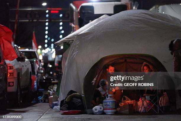 Anti-vaccine mandate protestors keep warm with a heater in a tent as they came out overnight at their barricade in front of the Ambassador Bridge...