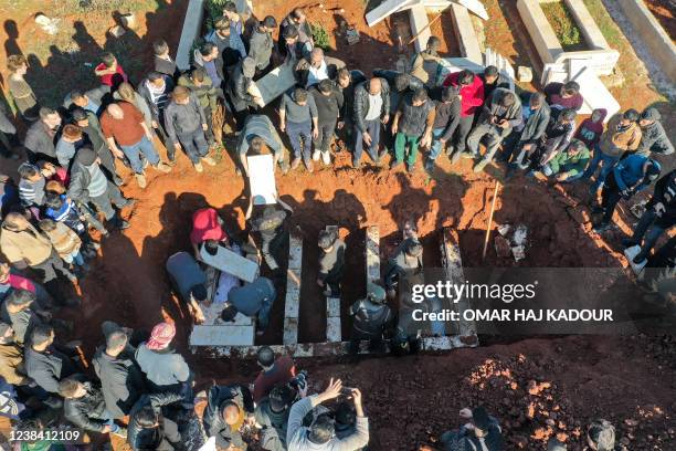 Graphic content / This picture taken on February 12, 2022 shows an aerial view of the burial of bodies of victims of reported bombardment by Syrian...