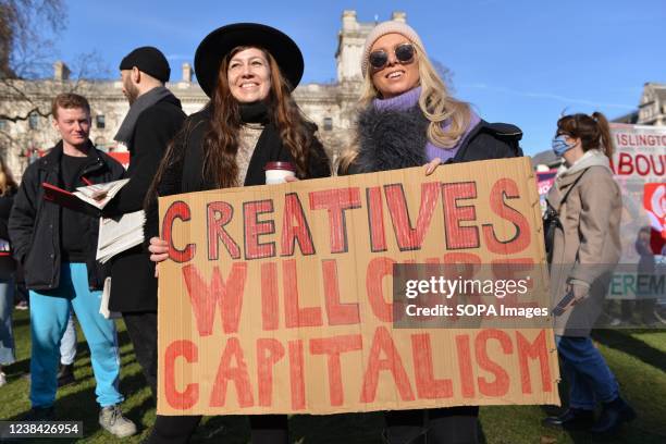 Protester holds a placard that says creatives will cure capitalism during the demonstration. Anti government protesters gathered at Parliament Square...