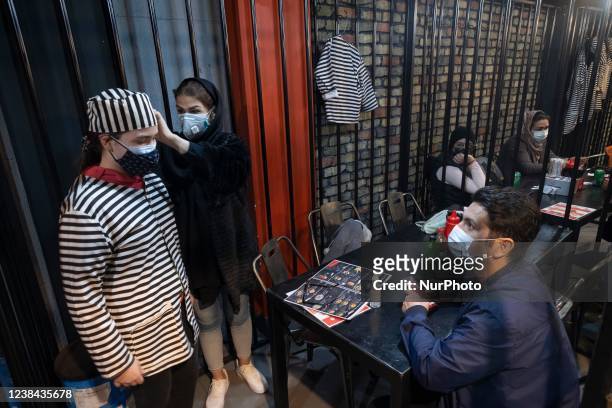 An Iranian woman helps her young daughter to wear a prisoner uniform as they stand at a cell while visiting the CELL-16 fast food jail restaurant...