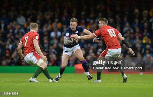 Stuart Hogg of Scotland takes on Dan Biggar of Wales and Jac Morgan during the Guinness Six Nations Round 2 match between Wales and Scotland at...