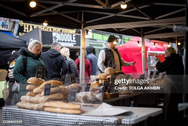 Customers shop for bread on a market stall in Walthamstow, east London on February 13, 2022. - UK annual inflation struck 5.4 percent in December,...