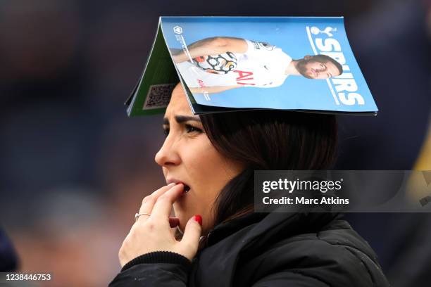 Tottenham Hotspur fan wears the match-day programme on her head as rain falls during the Premier League match between Tottenham Hotspur and...