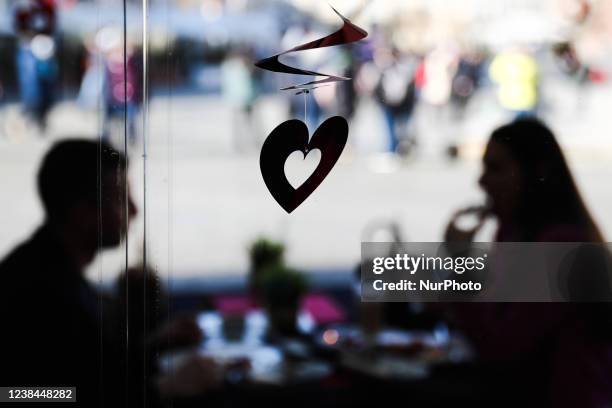 Heart-shaped decoration and a couple sitting at the table are seen in the restaurant, day before Valentine's Day, in Krakow, Poland on February 13,...