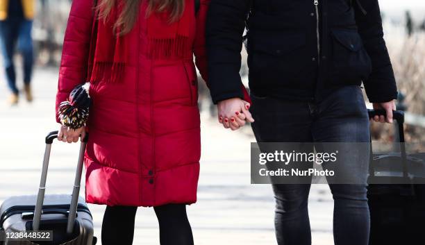 Couple are holding hands as they walk the street with their luggages in Krakow, Poland on February 13, 2022.