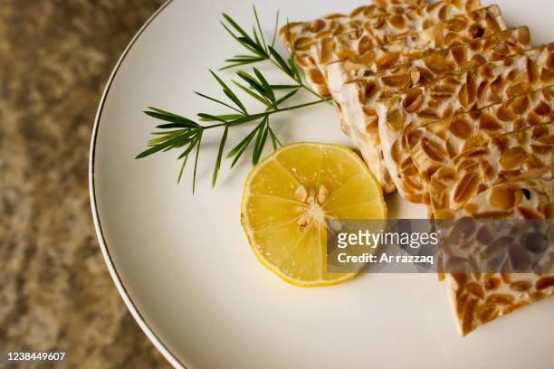 close-up tempeh with orange slices on a white plate - テンペ ストックフォトと画像