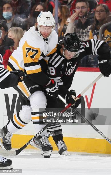 Jeff Carter of the Pittsburgh Penguins and Damon Severson of the New Jersey Devils battle for a loose puck during the game at Prudential Center on...