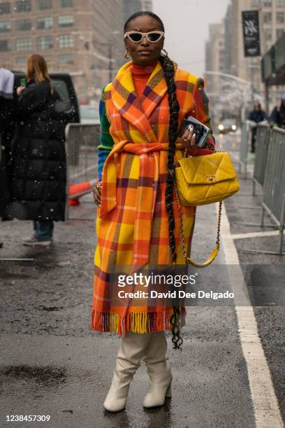 Tenicka Boyd wears a coat by Mira Mikati and a CHANEL handbag to New York Fashion Week at Spring Studios on February 13, 2022 in New York City.
