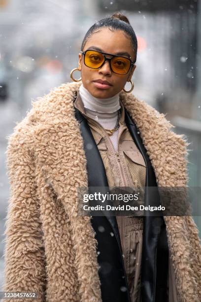 Kristian Spraggins wears a jumpsuit by Pretty Little Thing, blazer by Zara, boots by Marc Jacob, handbag by Gucci, teddy coat by H&M and jewelry by...