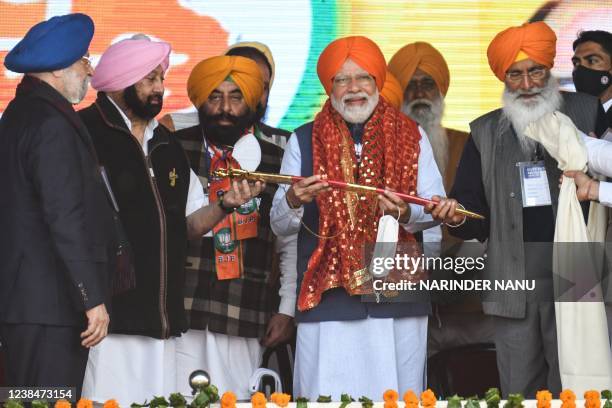 Indian Prime Minister Narendra Modi holds a sword presented by Union Minister Hardeep Singh Puri , Punjab Lok Congress leader and former Punjab Chief...