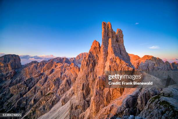 Summits and rock faces of Torri di Vajolet of Rosengarten group, seen from west above the mountain hut Rifugio Re Alberto I at sunset.