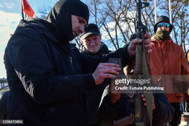 Participant of an open civil defence drill helps a boy to assemble an AK-74 automatic rifle in metropolitan Hydropark, Kyiv, capital of Ukraine