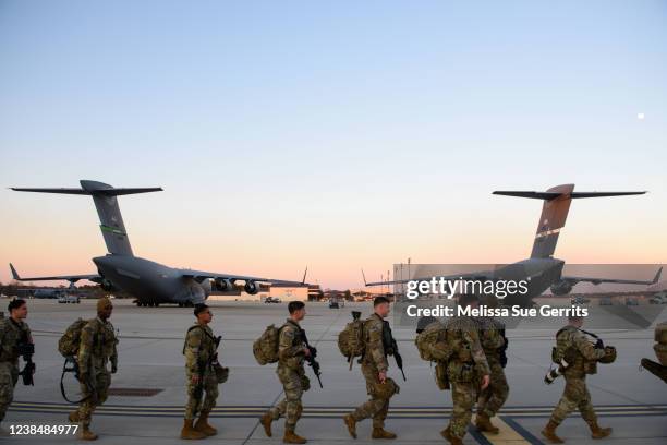 Soldiers with the 82nd Airborne division walk across the tarmac at Green Ramp to deploy to Poland on February 14, 2022 at Fort Bragg, Fayetteville,...