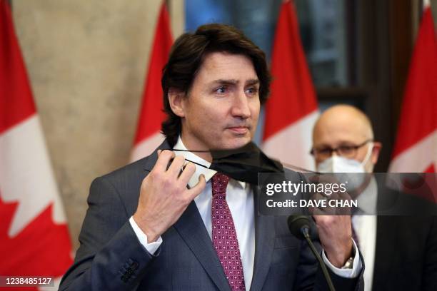 Canada's Prime Minister Justin Trudeau removes his mask during a news conference on Parliament Hill in Ottawa, Canada on February 14, 2022. -...