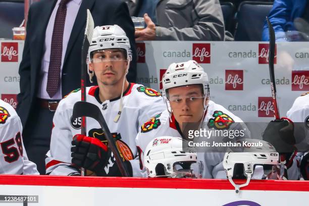 Dylan Strome and Henrik Borgstrom of the Chicago Blackhawks look on from the bench prior to puck drop against the Winnipeg Jets at the Canada Life...