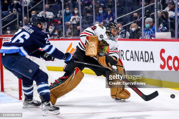 Goaltender Marc-Andre Fleury of the Chicago Blackhawks shoots the puck past Blake Wheeler of the Winnipeg Jets during first period action at the...