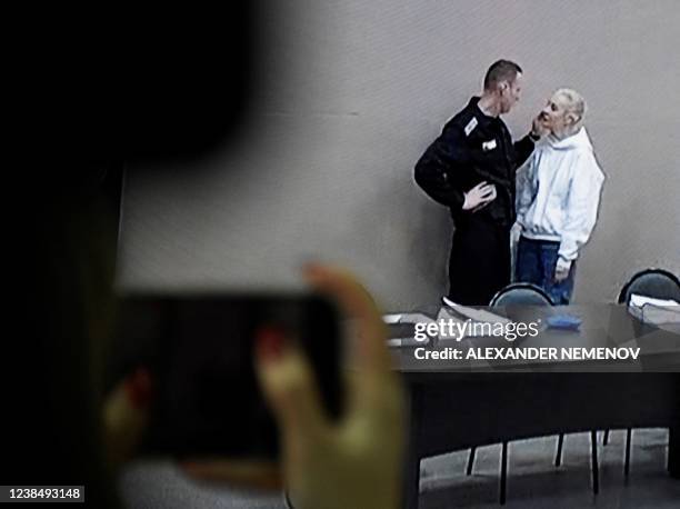 Journalists watch live broadcast from the press room showing Alexei Navalny speaking with his wife Yulia ahead of the court hearing at the penal...