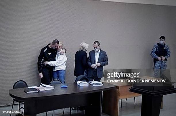Photograph taken from a TV screen during live broadcast of the court hearing at the penal colony N2 shows Kremlin critic Alexei Navalny embracing his...