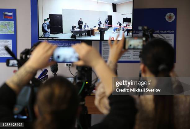 Members of the media take photographs of the screen showing Russian opposition politician Alexei Navalny at the penal colony during the trial on...