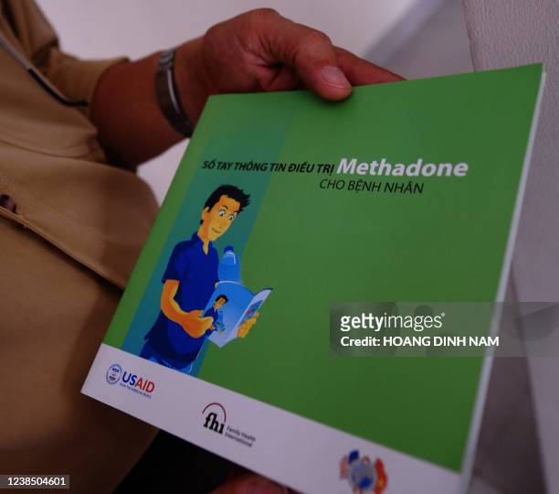 In a picture taken on July 8, 2010 parents a man holds a pamphlet about methadone treatment programme at a methadone clinic in the southern city of...
