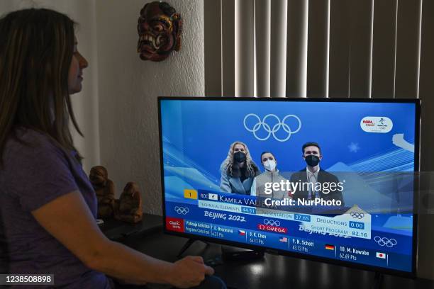 Woman watches Russian ice skater, Kamila Valieva, competing in the women's singles event at the Beijing Winter Olympics 2022. On Tuesday, February 15...